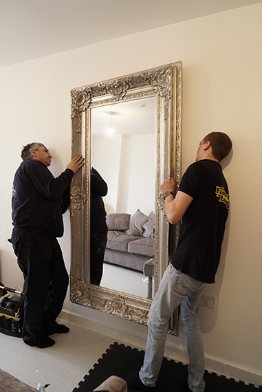 Handyman team fitting a mirror in a London property